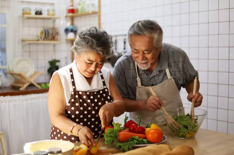 Husband and wife cooking a nice, health dinner together in the kitchen. Focusing on their digestive health.