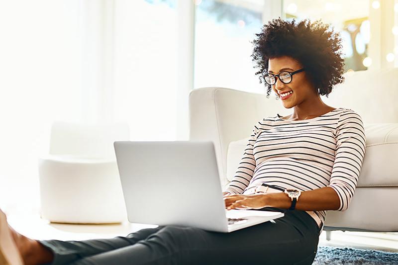 African American woman with glasses working on her laptop.