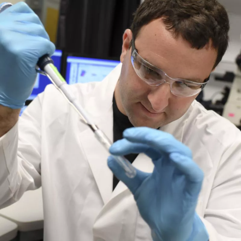 A male researcher examines a test tube in the hospital lab.