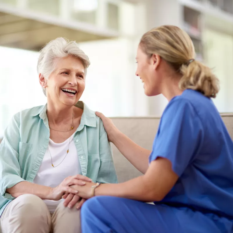 A Smiling Senior Patient Speaks to a Nurse in the Waiting Room