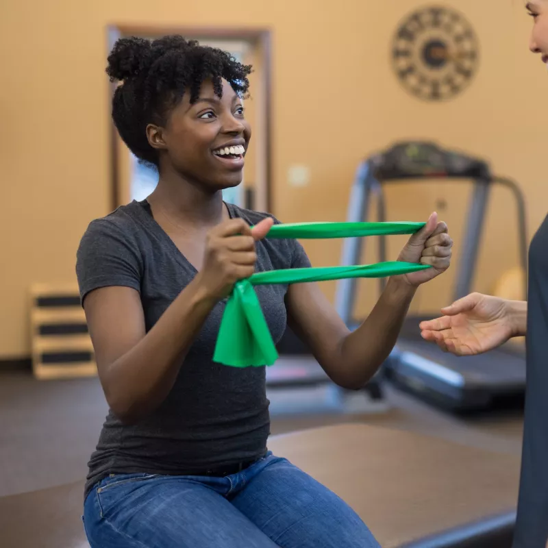 A woman does strengthening exercises with her physical therapist.